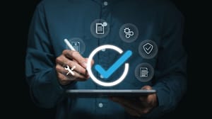 A hand on a tablet with a circle and a check above it surrounded by digital icons A hand on a tablet with a circle and a check above it surrounded by digital icons