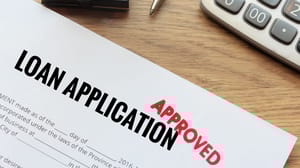 A red stamp that says approved on a paper loan application A red stamp that says approved on a paper loan application