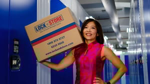 A woman holding a box standing by a self-storage unit A woman holding a box standing by a self-storage unit