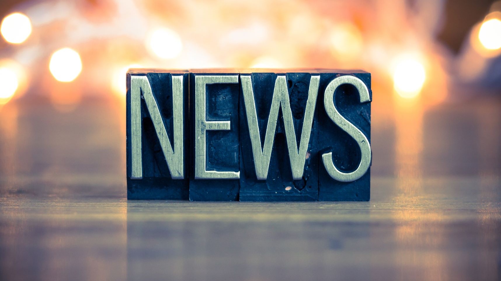 The word news in tall letters on a metal plate background
