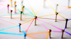 An image of many screws upright with colorful thread wrapped around them and connecting them to one another An image of many screws upright with colorful thread wrapped around them and connecting them to one another