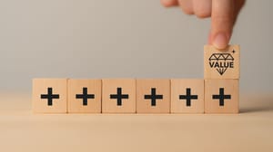 An image of square tiles with plus signs with a hand holding a tile with a crown An image of square tiles with plus signs with a hand holding a tile with a crown