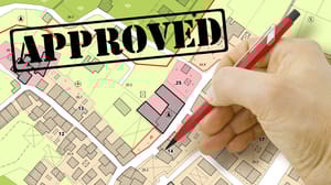A colorful map of parcels with hand holding a pen marking one and the word approved above it A colorful map of parcels with hand holding a pen marking one and the word approved above it