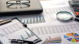 An image with market charts and graphic, a pair of glasses, a calculator and a magnifying glass An image with market charts and graphic, a pair of glasses, a calculator and a magnifying glass