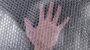 An image of sheet of bubble wrap with a hand in the center facing palm out An image of sheet of bubble wrap with a hand in the center facing palm out