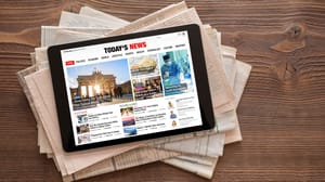 An image of news on a tablet on a stack of newspapers. An image of news on a tablet on a stack of newspapers.