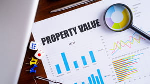 Property value on a document with charts and graphics and a magnigying glass Property value on a document with charts and graphics and a magnigying glass