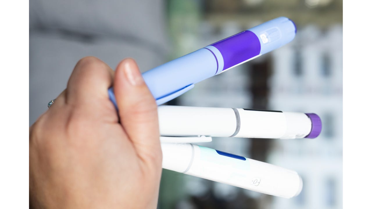 Hand holding three semaglutide and insulin injection pens Hand holding three semaglutide and insulin injection pens