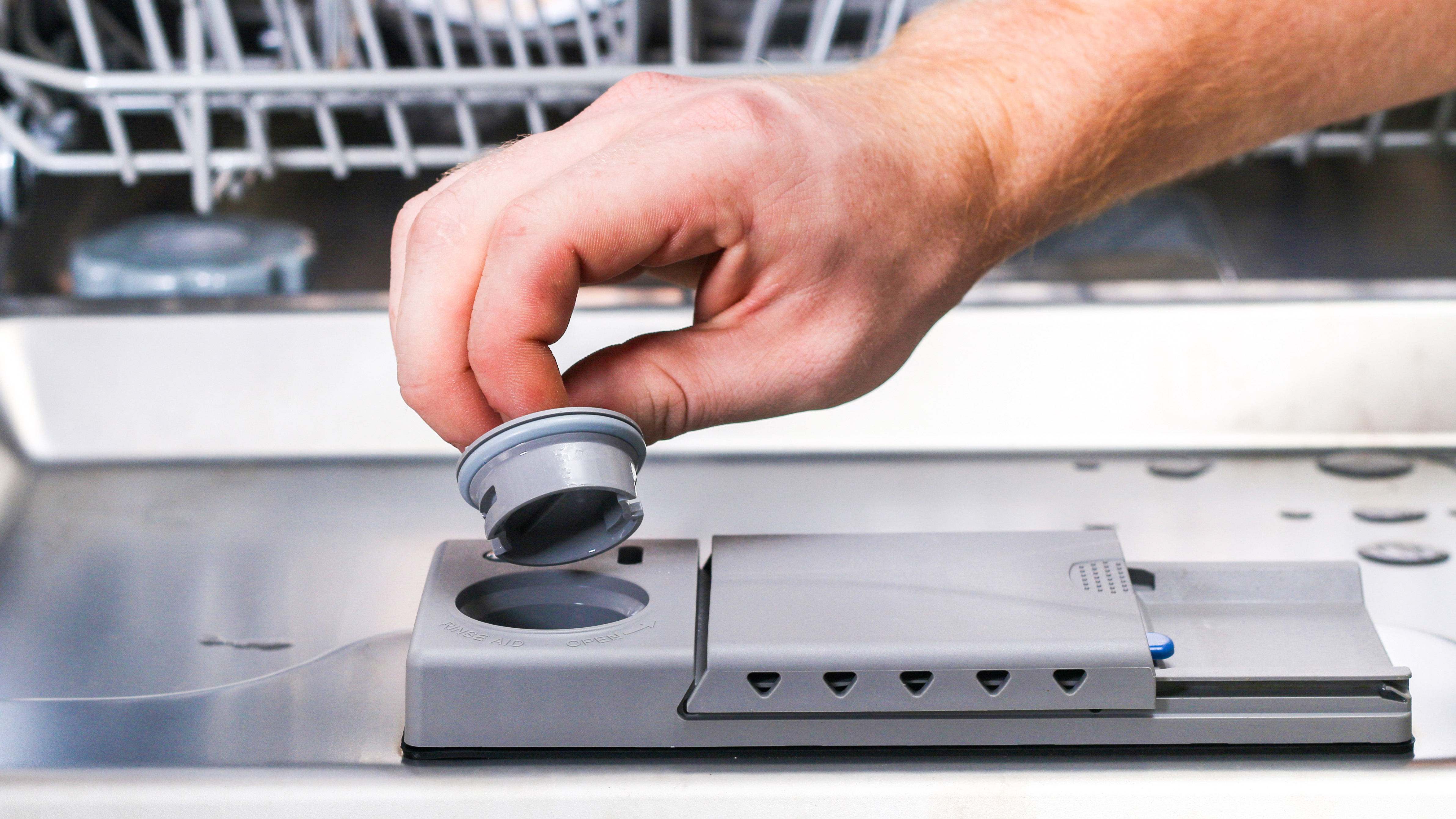 Adding Finish Rinse Aid to dishwasher dispenser for cleaner dishes and protection against hard water buildup.