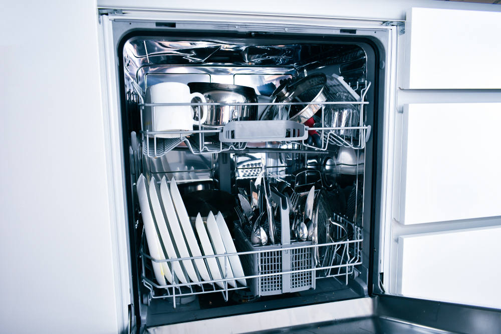 Intérieur du lave-vaisselle ouvert, rempli d’assiettes, de tasses et de couverts, pour montrer les économies d'eau obtenues lors d’un lavage à pleine charge.