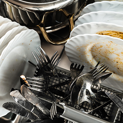 Soiled dishes, cutlery and a pot inside a dishwasher.