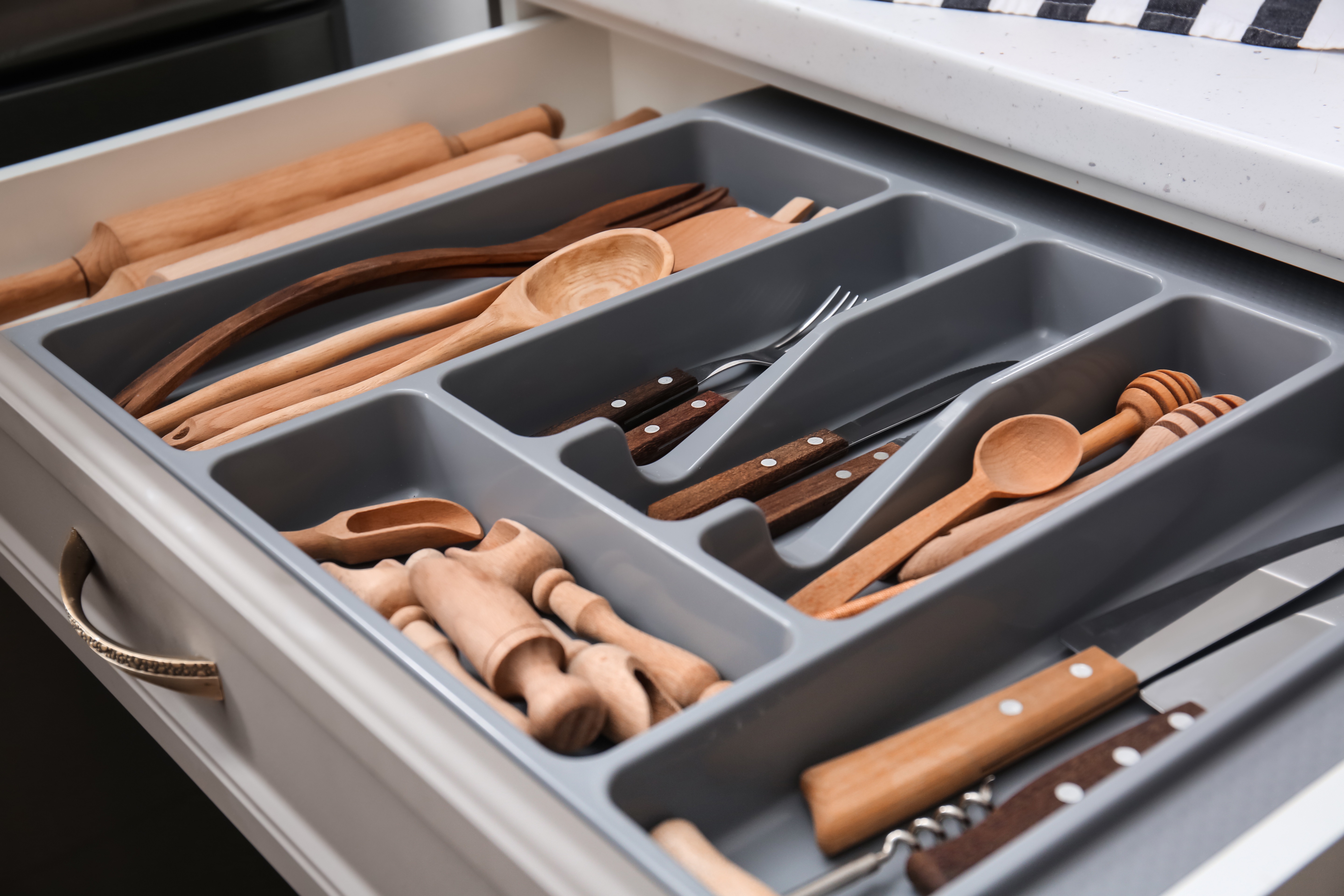 A grey drawer filled with wooden utensils.