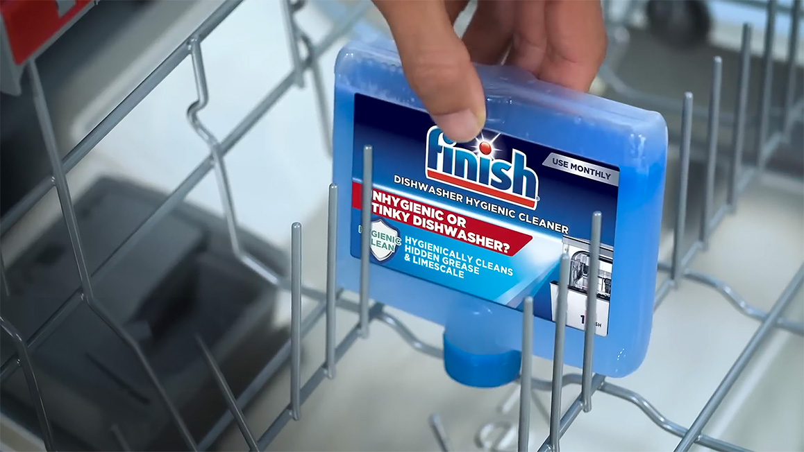 A blue Finish Dishwasher Cleaner bottle rests upside down in a dishwasher.
