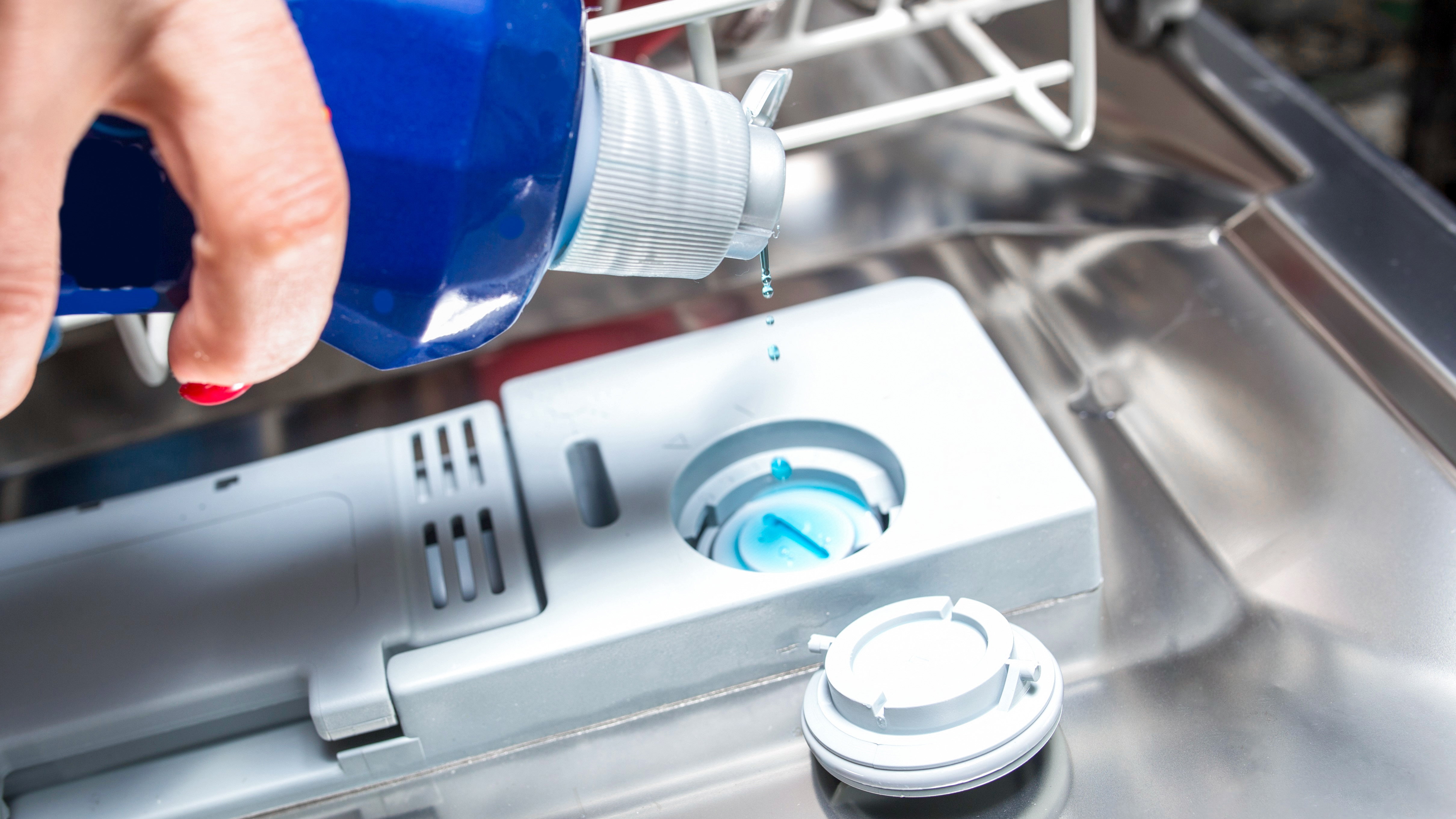 Hand showing where to add Finish Rinse Aid in a dishwasher dispenser to help remove hard water stains.