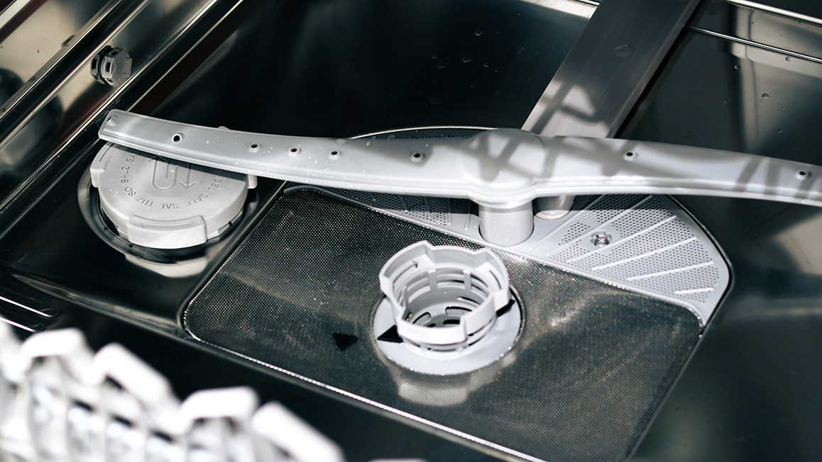 Closeup of the filter and spraying arm inside a dishwasher.