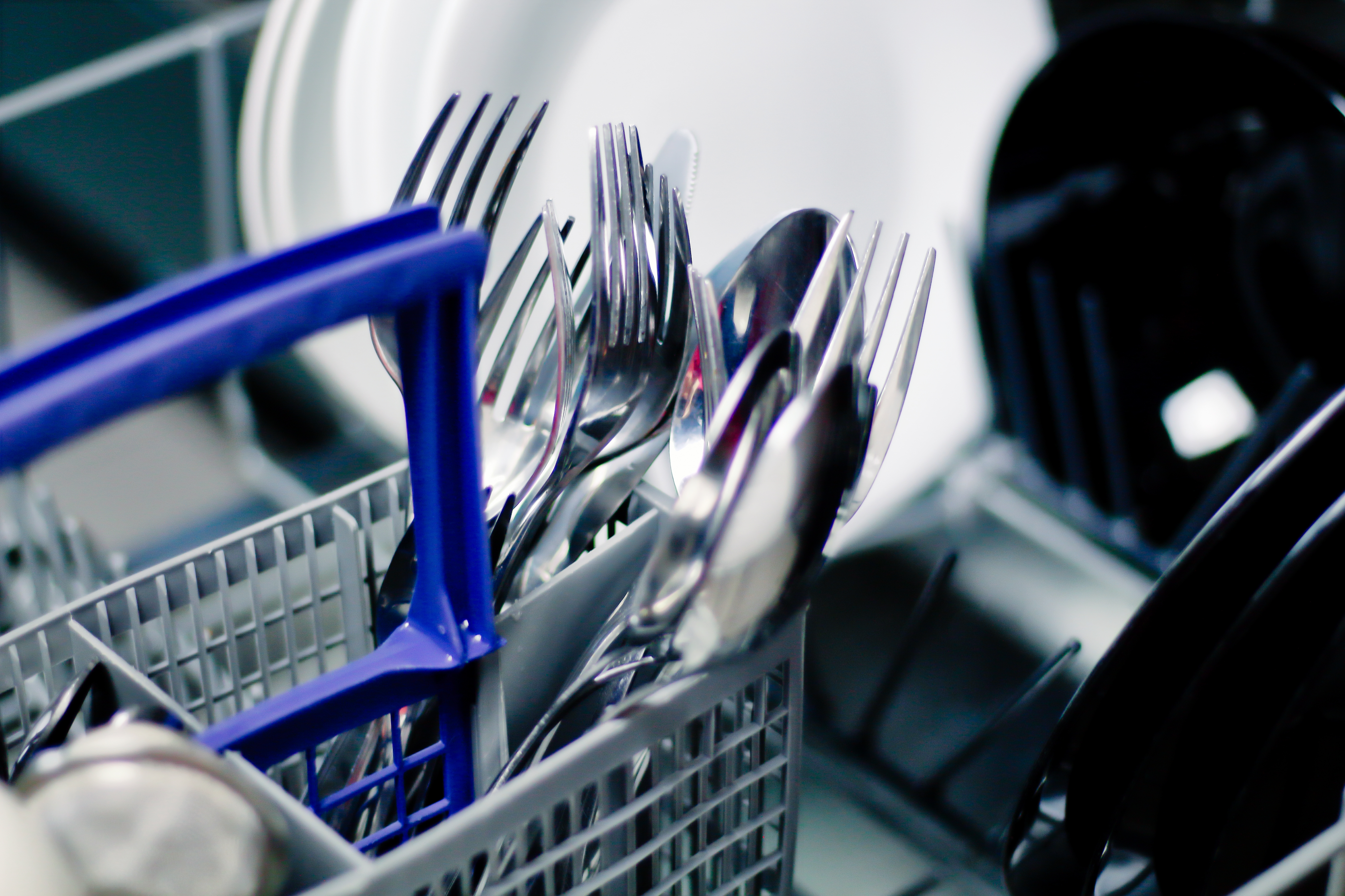 A full cutlery rack inside a dishwasher.