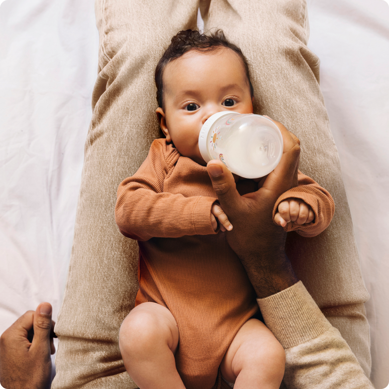 Baby-zit-op-schoot-en-drinkt-uit-een-fles.png