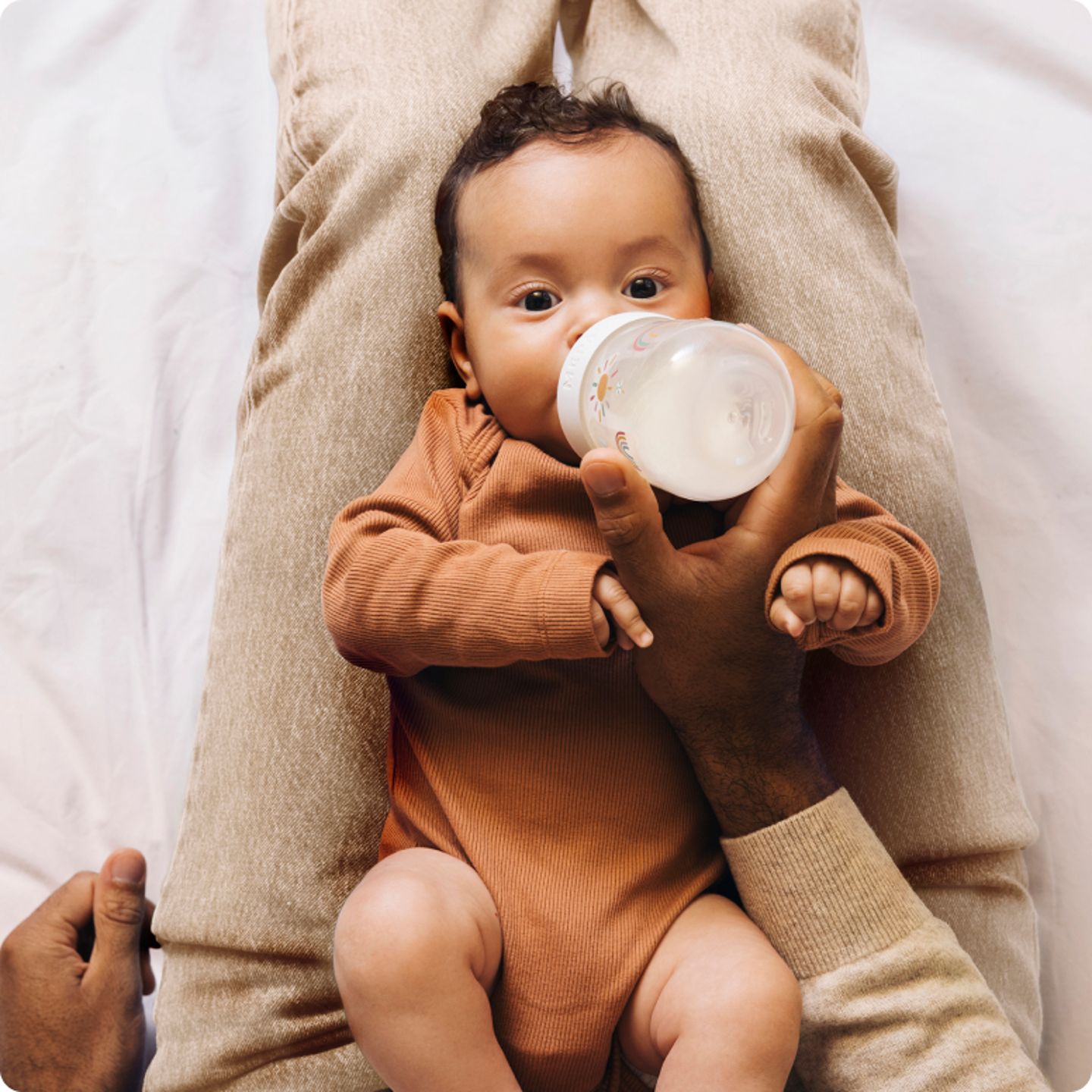 Baby-zit-op-schoot-en-drinkt-uit-een-fles.png