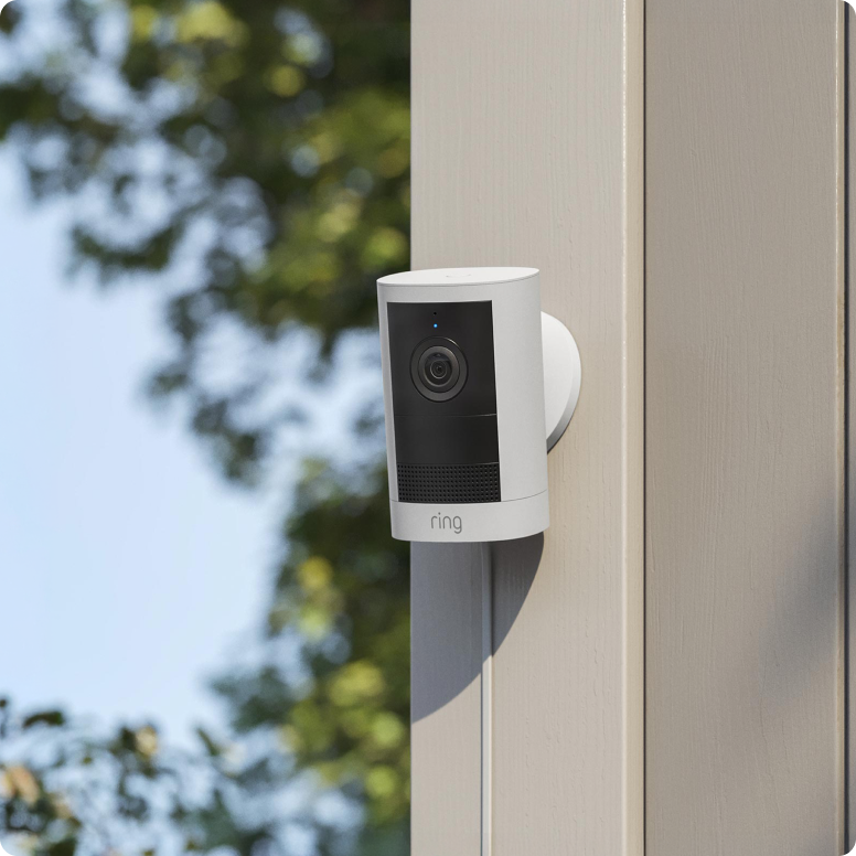 Witte-ringcamera-bevestigd-aan-een-houten-paal-buiten.png