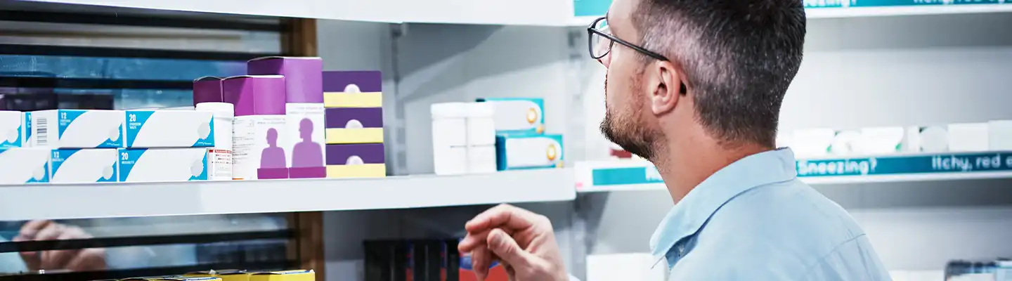 man looking at medicine on shelf