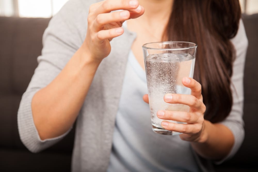 Mujer tomando un vaso de antiácido efervescente