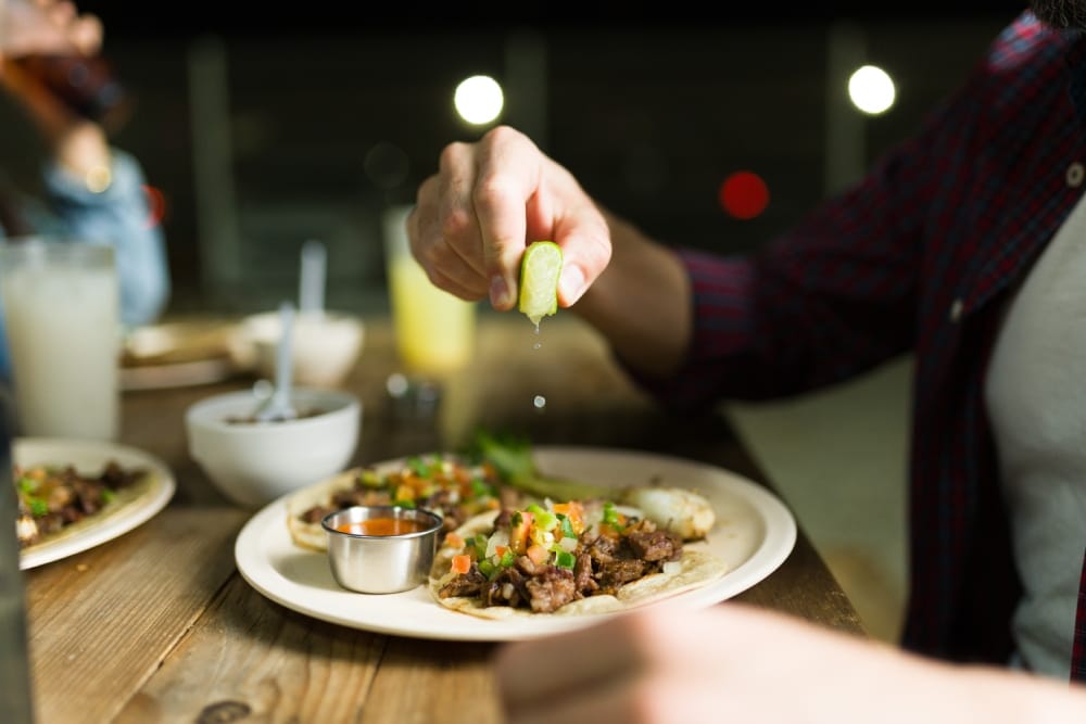 Persona exprimiendo un limón sobre tacos