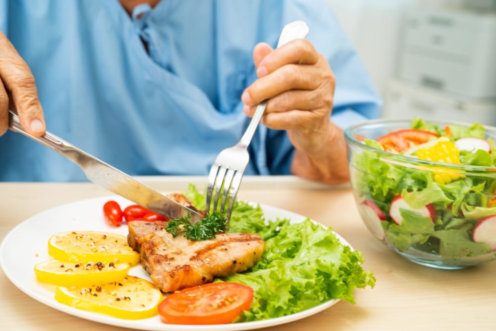 Persona comiendo ensalada y pescado