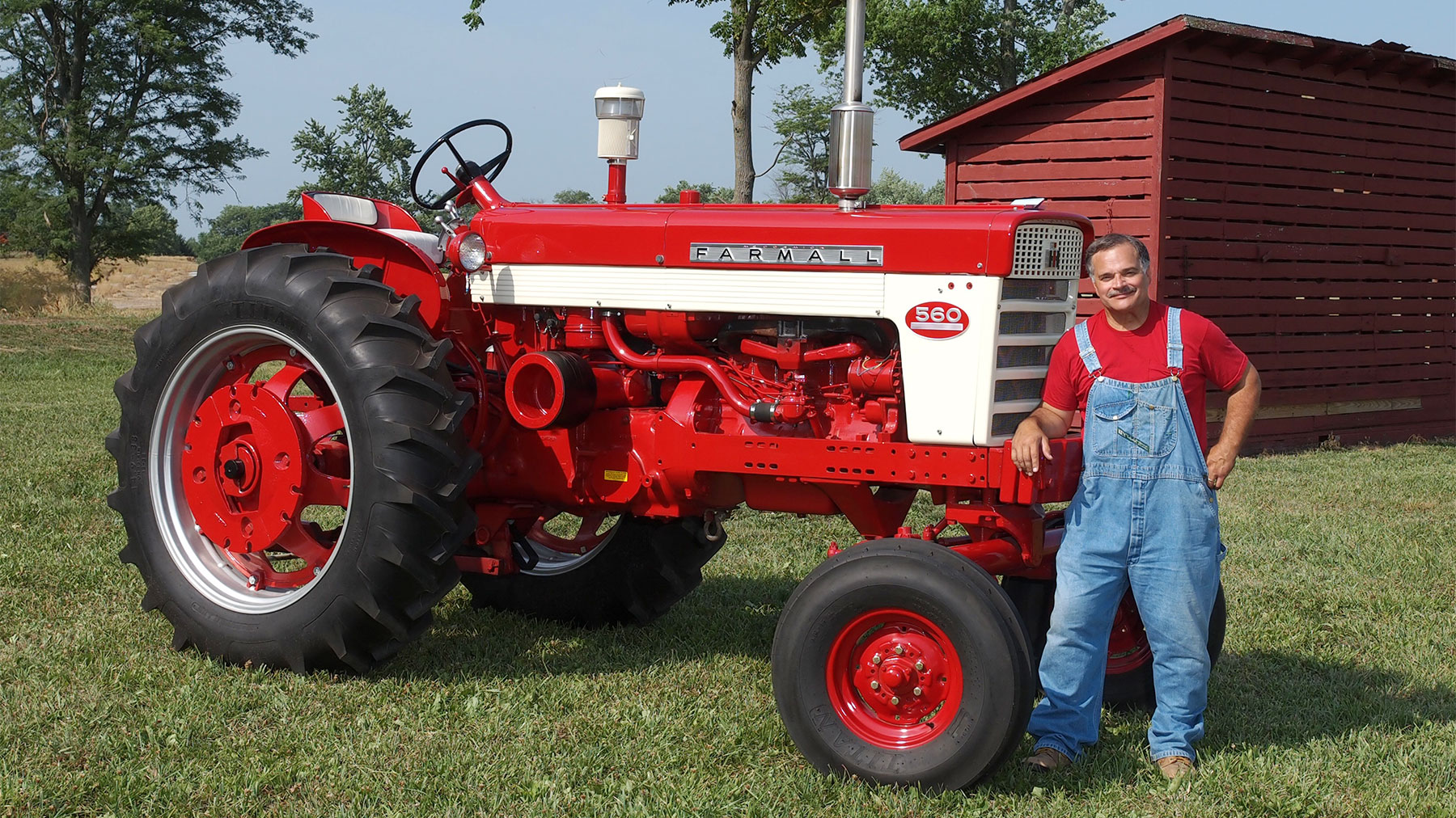 Max Armstrong stands next to a Farmall 560 tractor
