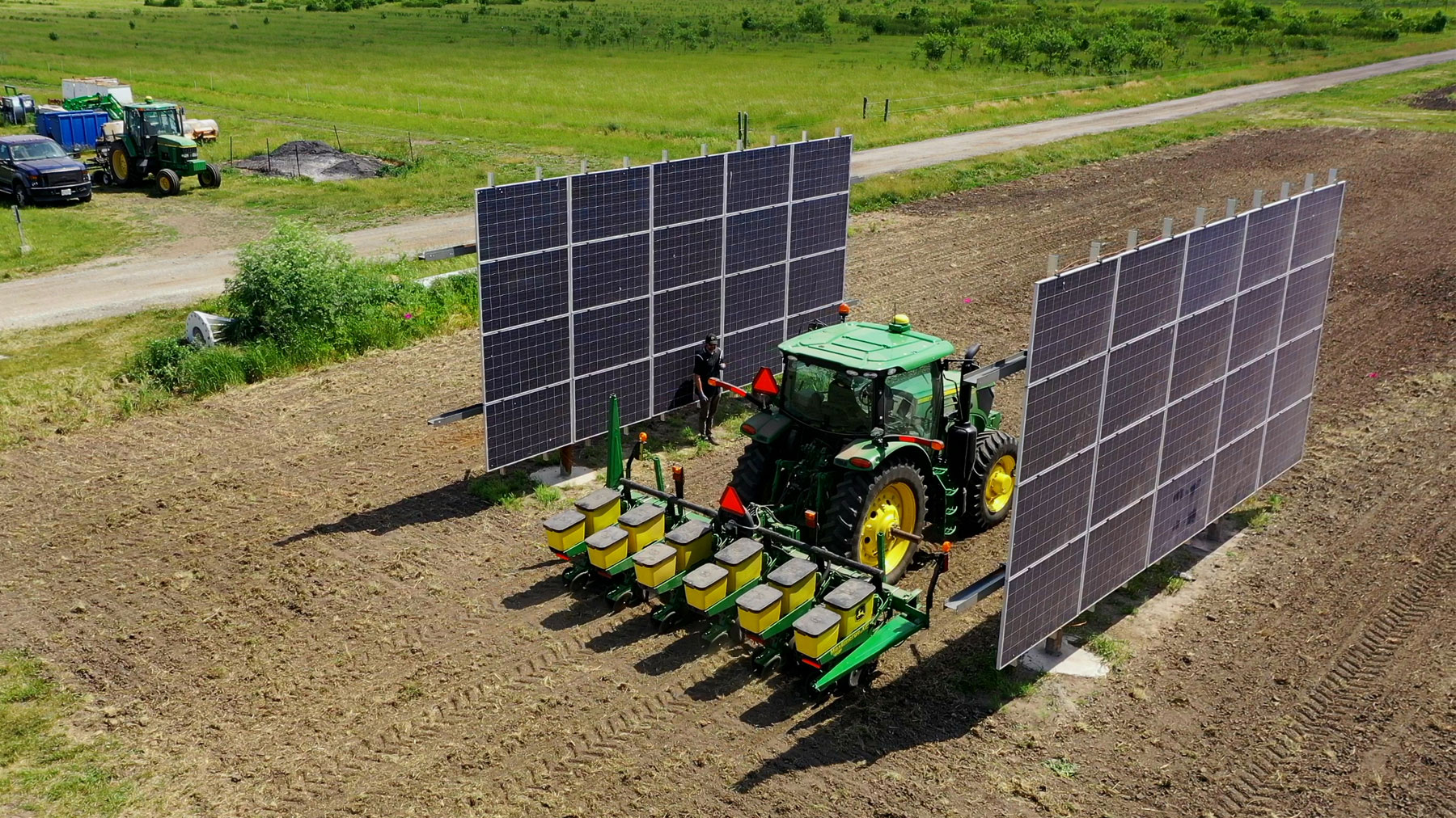 Tractor and planter in field between solar panels