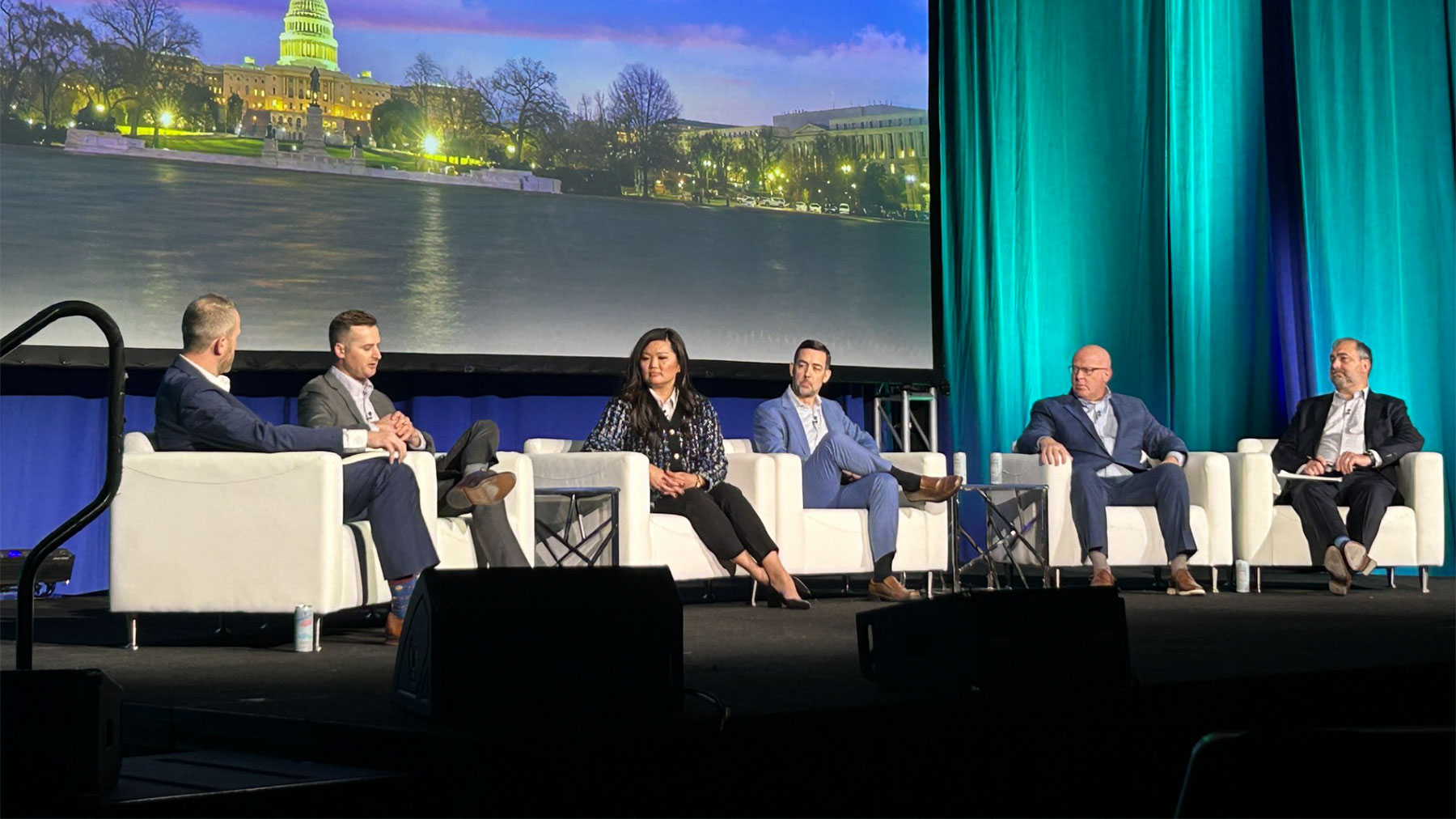 A group of panelist sitting in chairs on a stage
