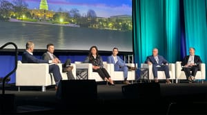 A group of panelist sitting in chairs on a stage A group of panelist sitting in chairs on a stage