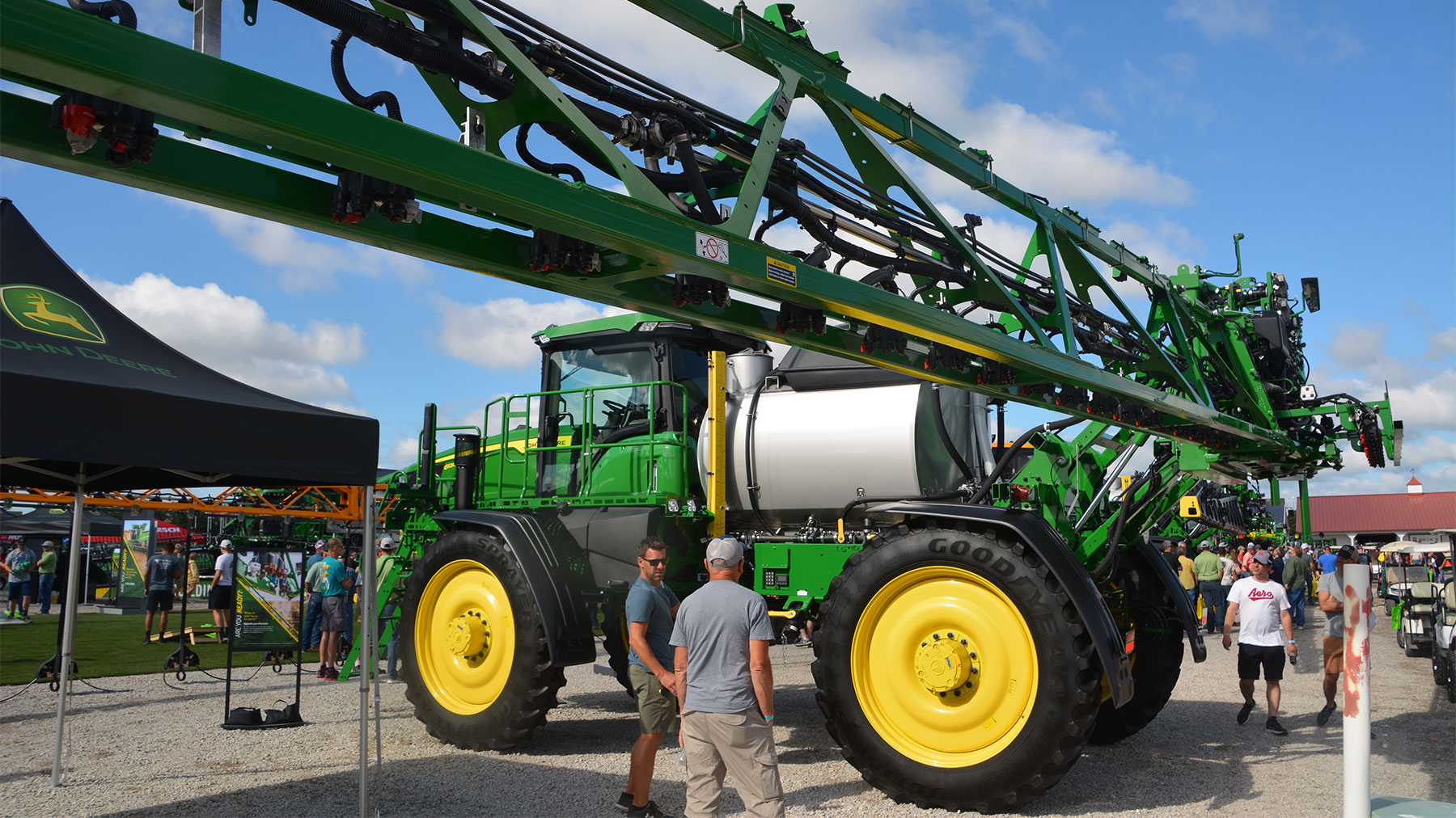 Farm show visitors gather around a John Deere sprayer on display